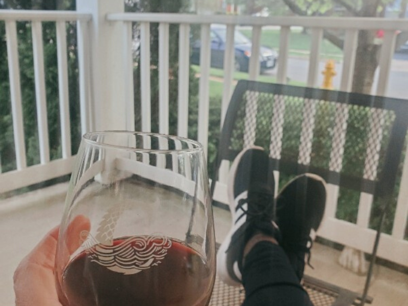 picture of woman sitting on porch with wine, all you see is her feet propped up and the wine glass, summertime, front porch